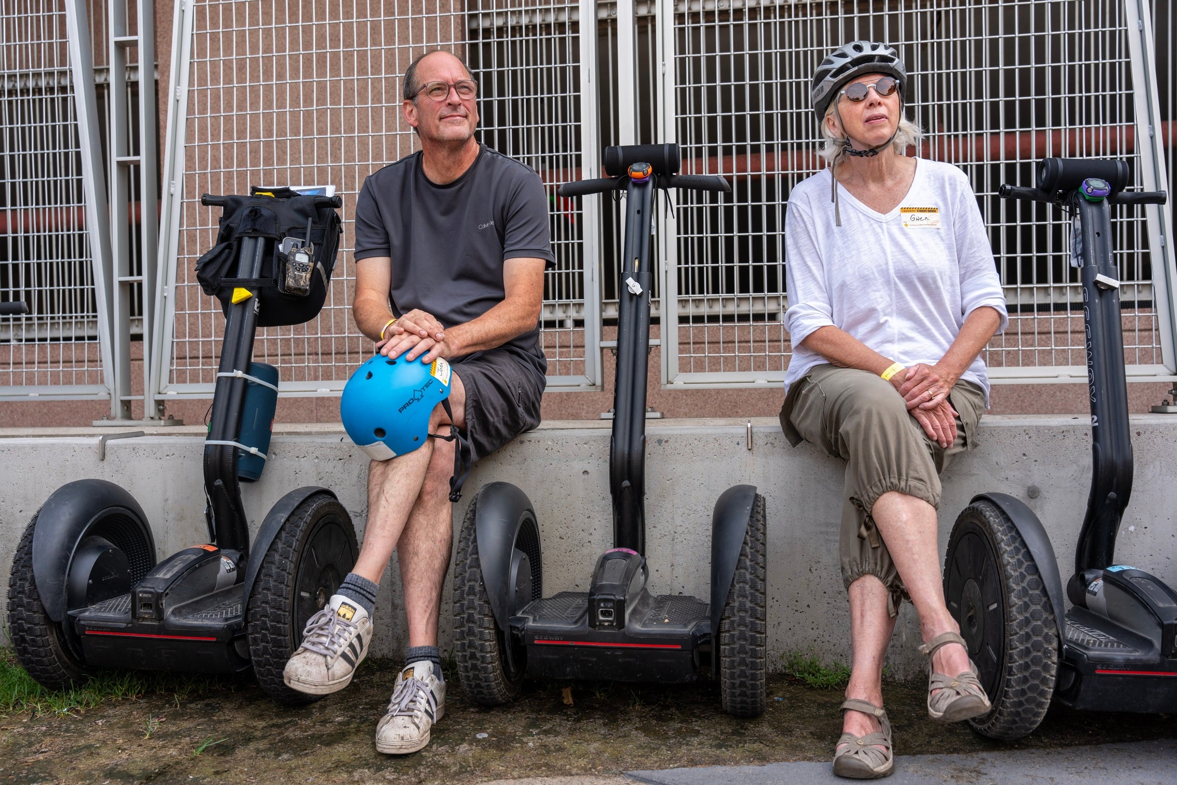Two helmeted Human on a Stick tour guests resting beside their Segway personal transporters during a guided Minneapolis micro-mobility tour
